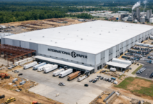 Large white International Paper distribution center with trucks at loading docks and construction around the building