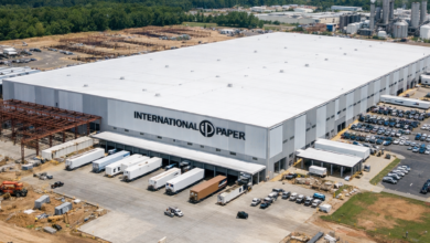 Large white International Paper distribution center with trucks at loading docks and construction around the building