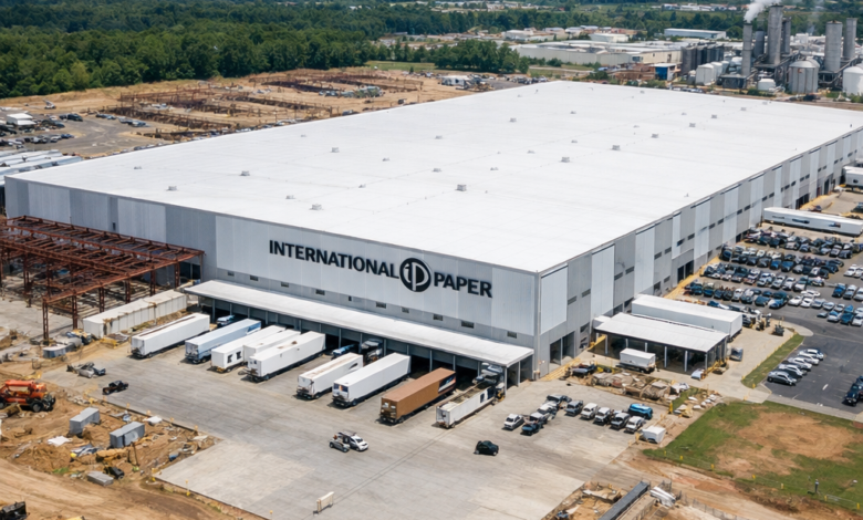 Large white International Paper distribution center with trucks at loading docks and construction around the building