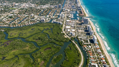 Aerial view of a coastal city bordered by wetlands and the ocean with buildings and waterways