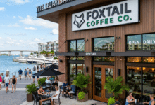 Outdoor seating area of Foxtail Coffee Co. at The Quay Sarasota with people sitting and walking along the waterfront