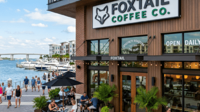 Outdoor seating area of Foxtail Coffee Co. at The Quay Sarasota with people sitting and walking along the waterfront