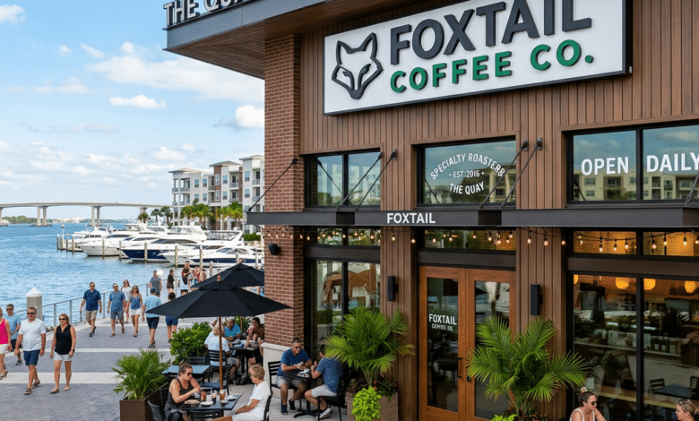 Outdoor seating area of Foxtail Coffee Co. at The Quay Sarasota with people sitting and walking along the waterfront