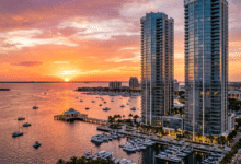Sun setting over marina with boats and two tall glass buildings