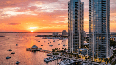 Sun setting over marina with boats and two tall glass buildings
