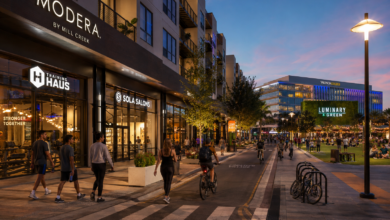 Street-level evening view of Modera Creative Village, active retail storefronts, pedestrians and cyclists beside Luminary Green in Downtown Orlando.